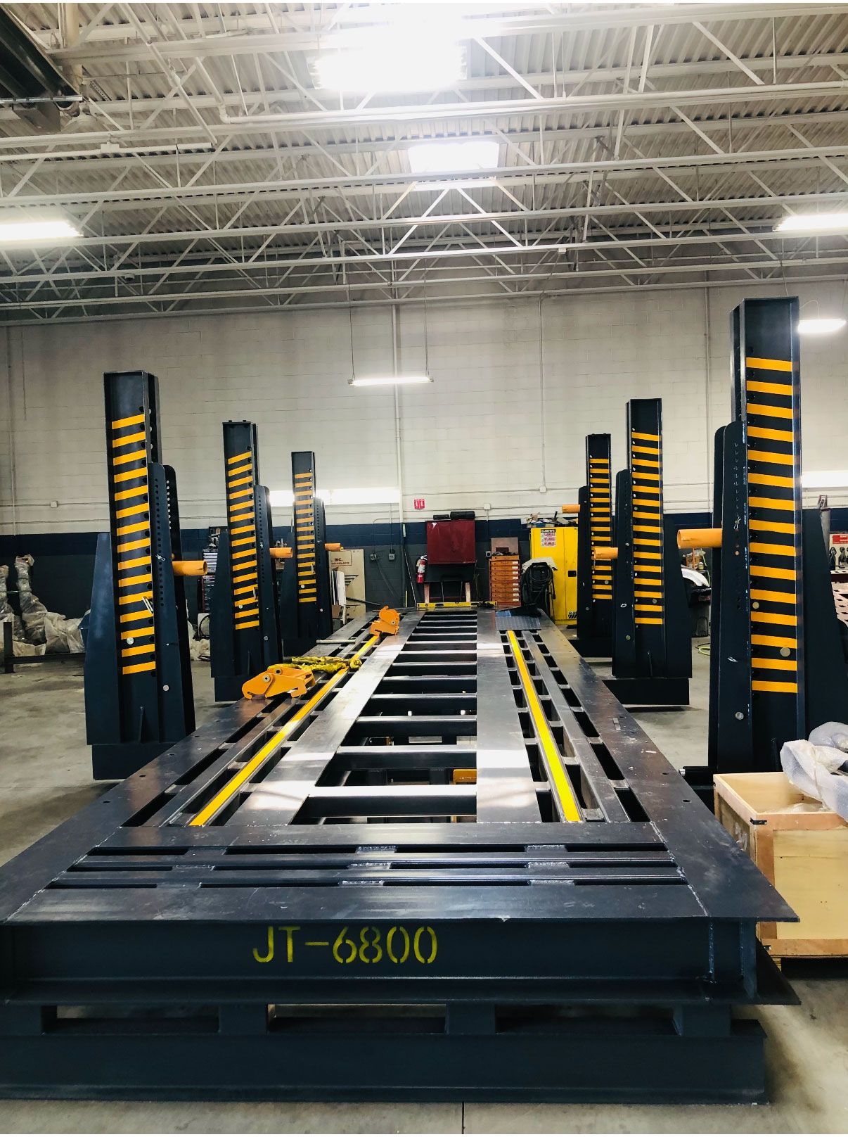 A heavy-duty JT-6800 vehicle frame machine with vertical hydraulic lift columns in an industrial workshop.
