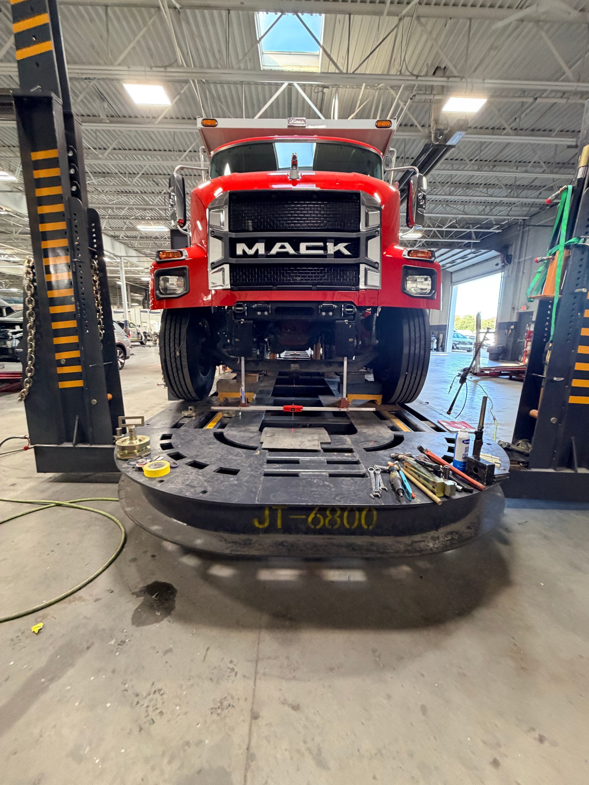 A red Mack truck sits on a large circular industrial lift inside a maintenance garage.