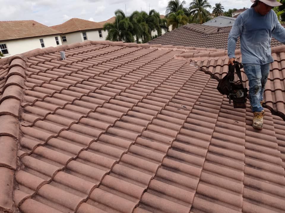 A man is standing on top of a tiled roof.