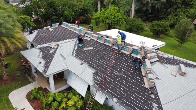 A group of people are working on the roof of a house.