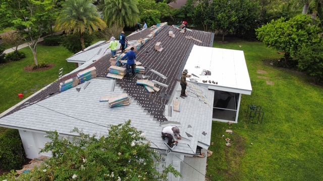 A group of people are working on the roof of a house.