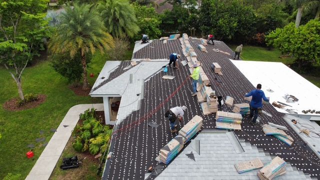 A group of people are working on the roof of a house.