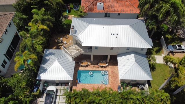 An aerial view of a house with a pool and a car parked in front of it.