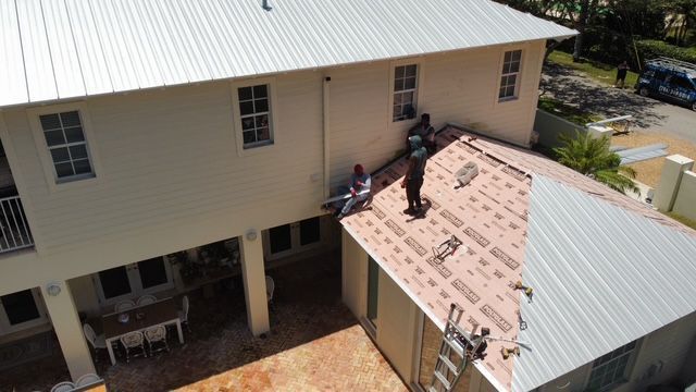 A group of people are working on the roof of a house.