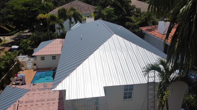 An aerial view of a house with a metal roof and a pool.