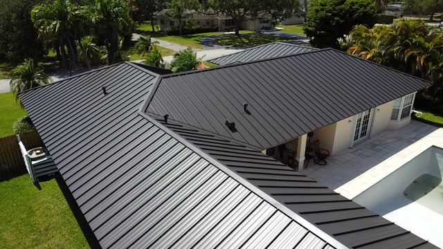 An aerial view of a house with a black roof and a pool.