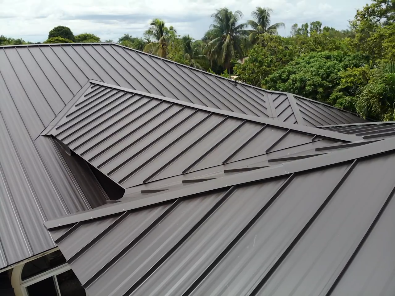 A brown metal roof with trees in the background.