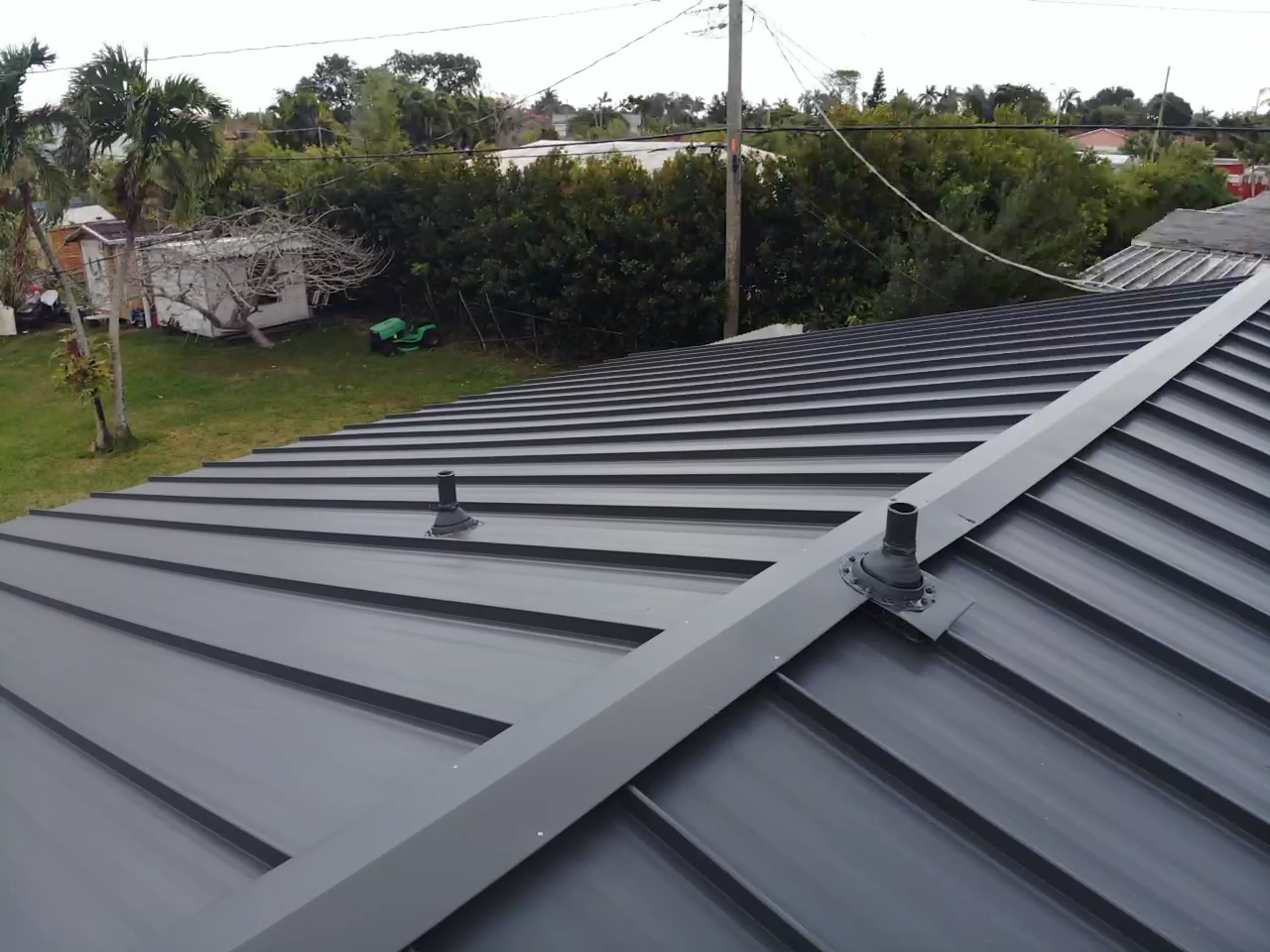 A black metal roof with a chimney on the side of it.