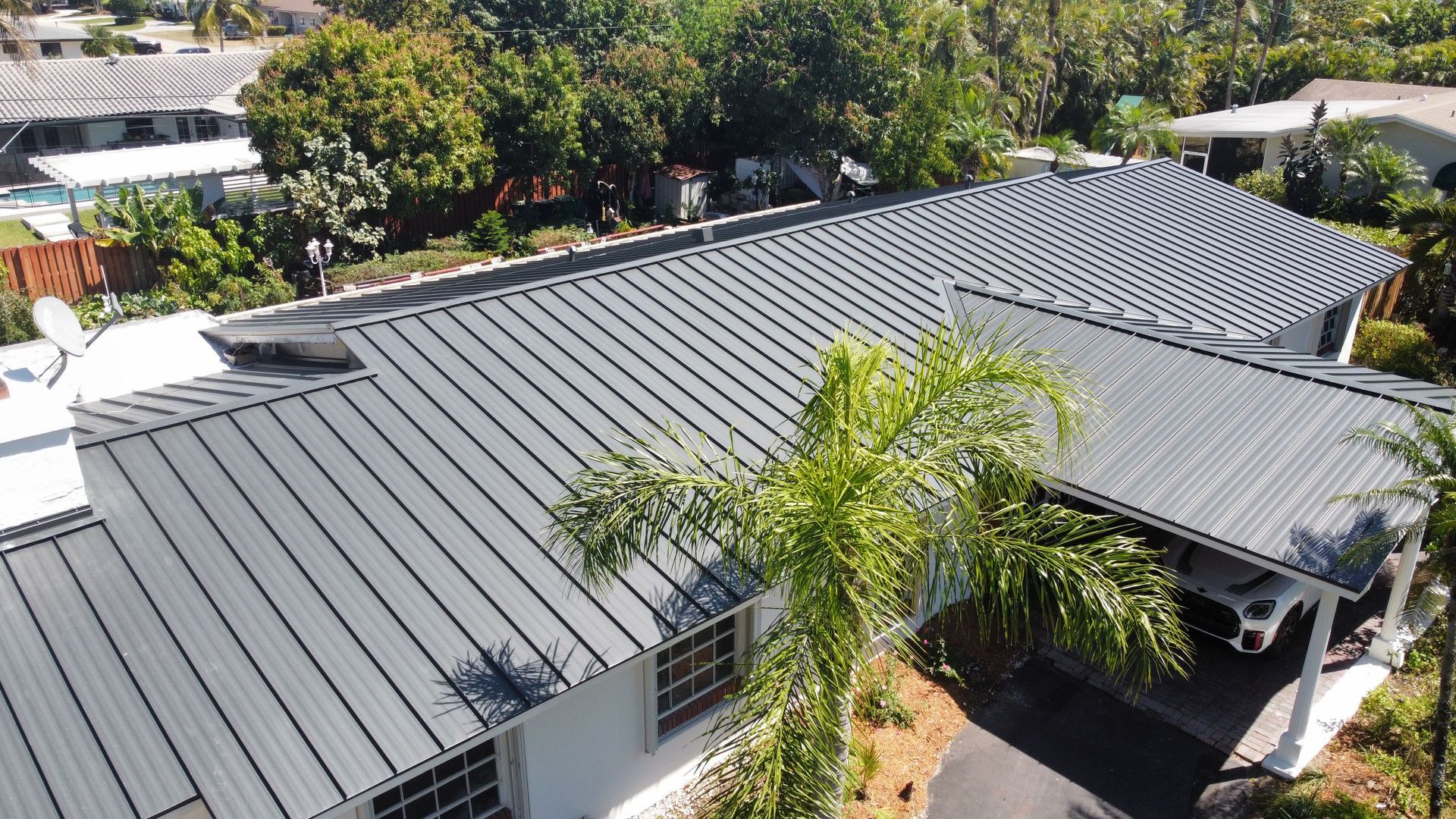 An aerial view of a house with a metal roof and a car parked in front of it.