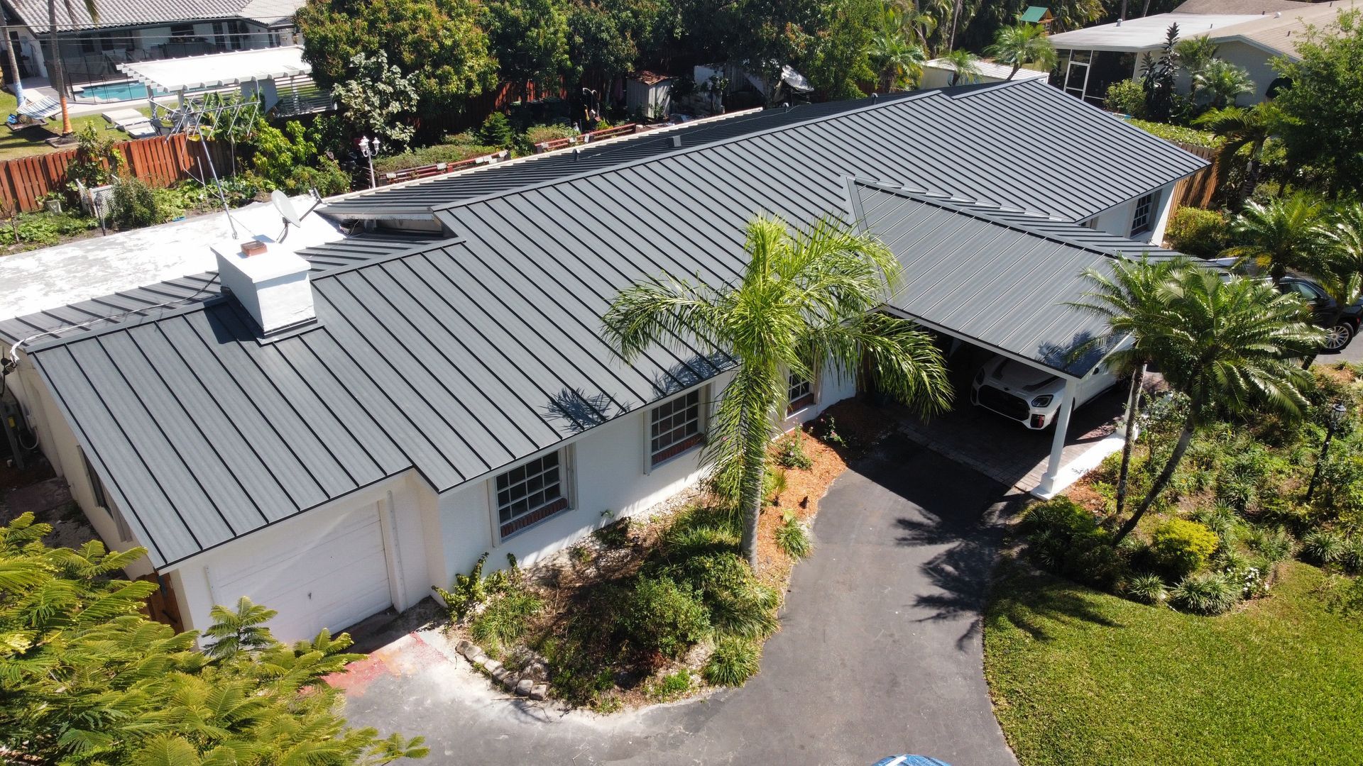An aerial view of a house with a metal roof and a driveway.