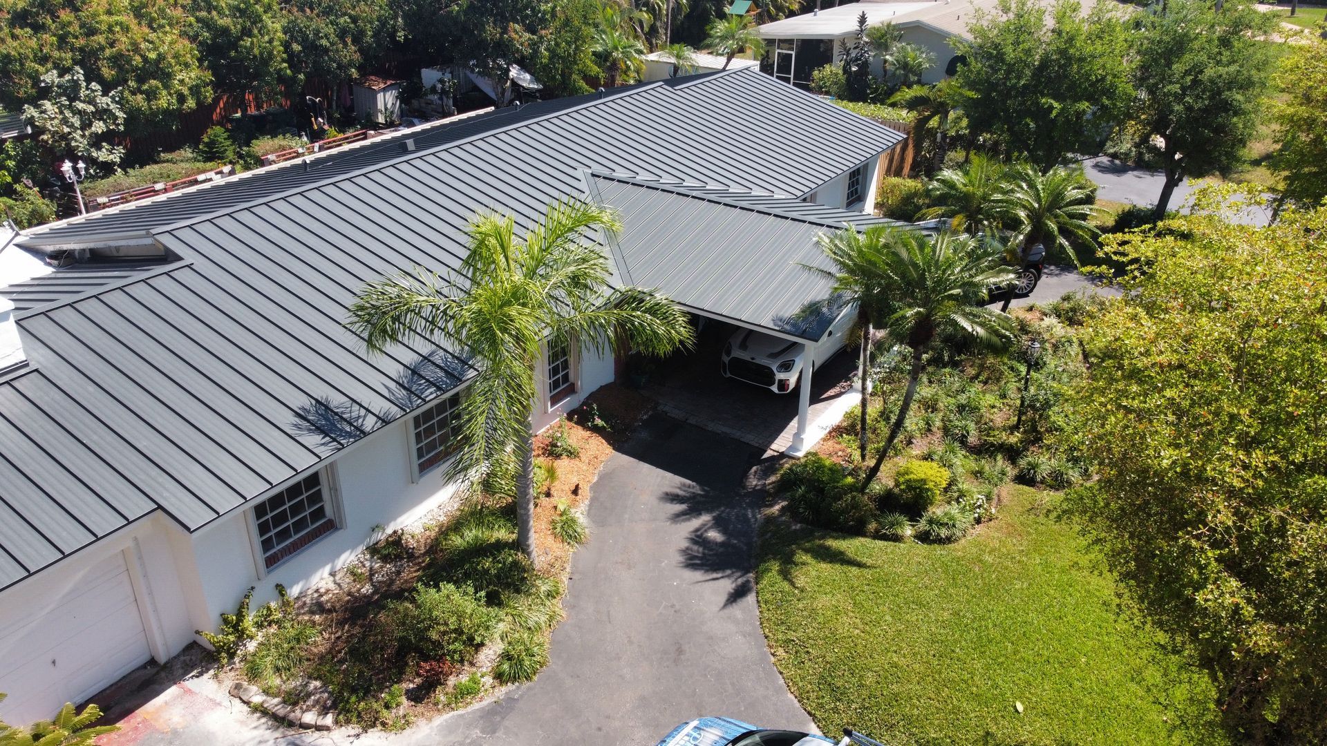 An aerial view of a house with a black roof and a driveway.