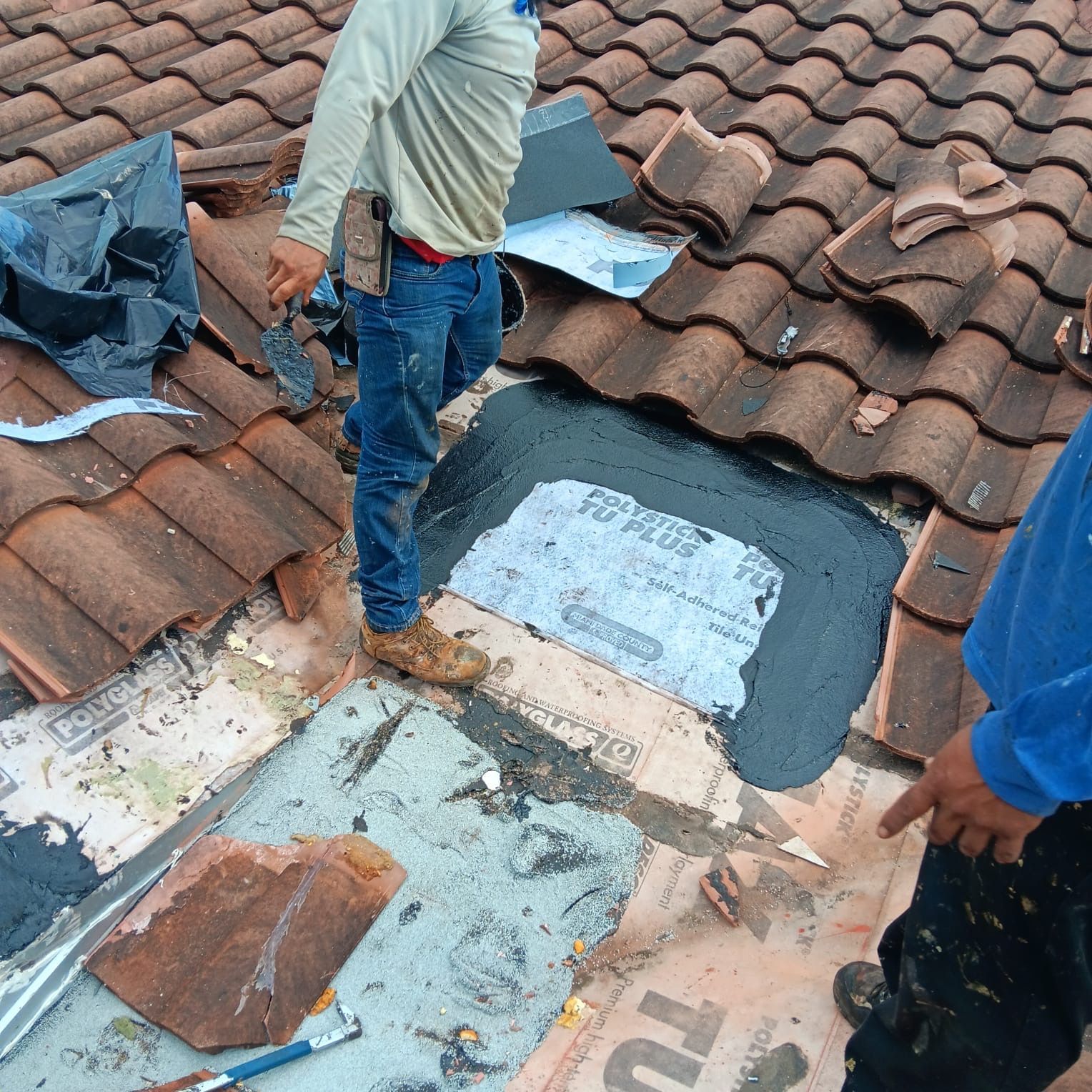 A man is standing on top of a tiled roof.