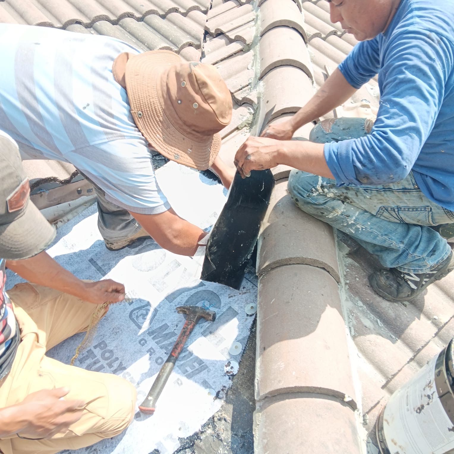 Two men are working on a roof and one has a hammer.