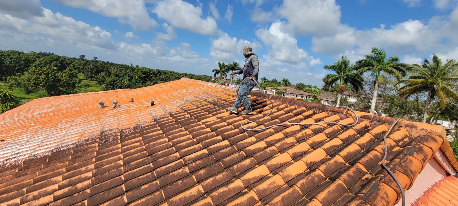A man is standing on top of a tiled roof.