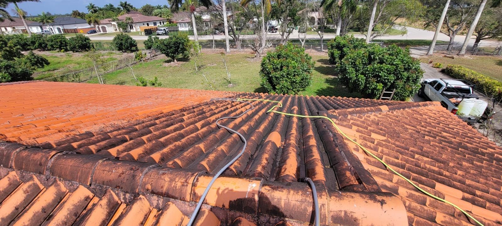 A person is cleaning a tiled roof with a hose.