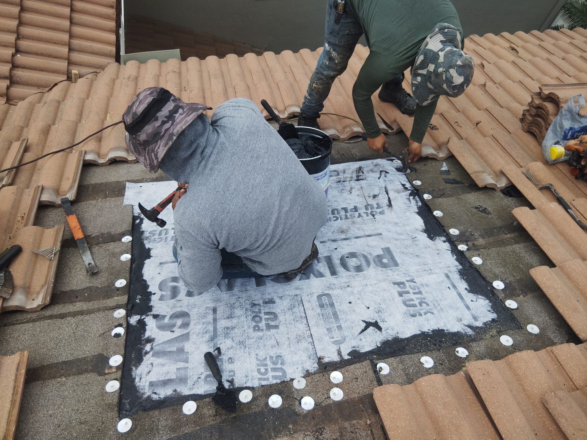Two men are working on the roof of a house.
