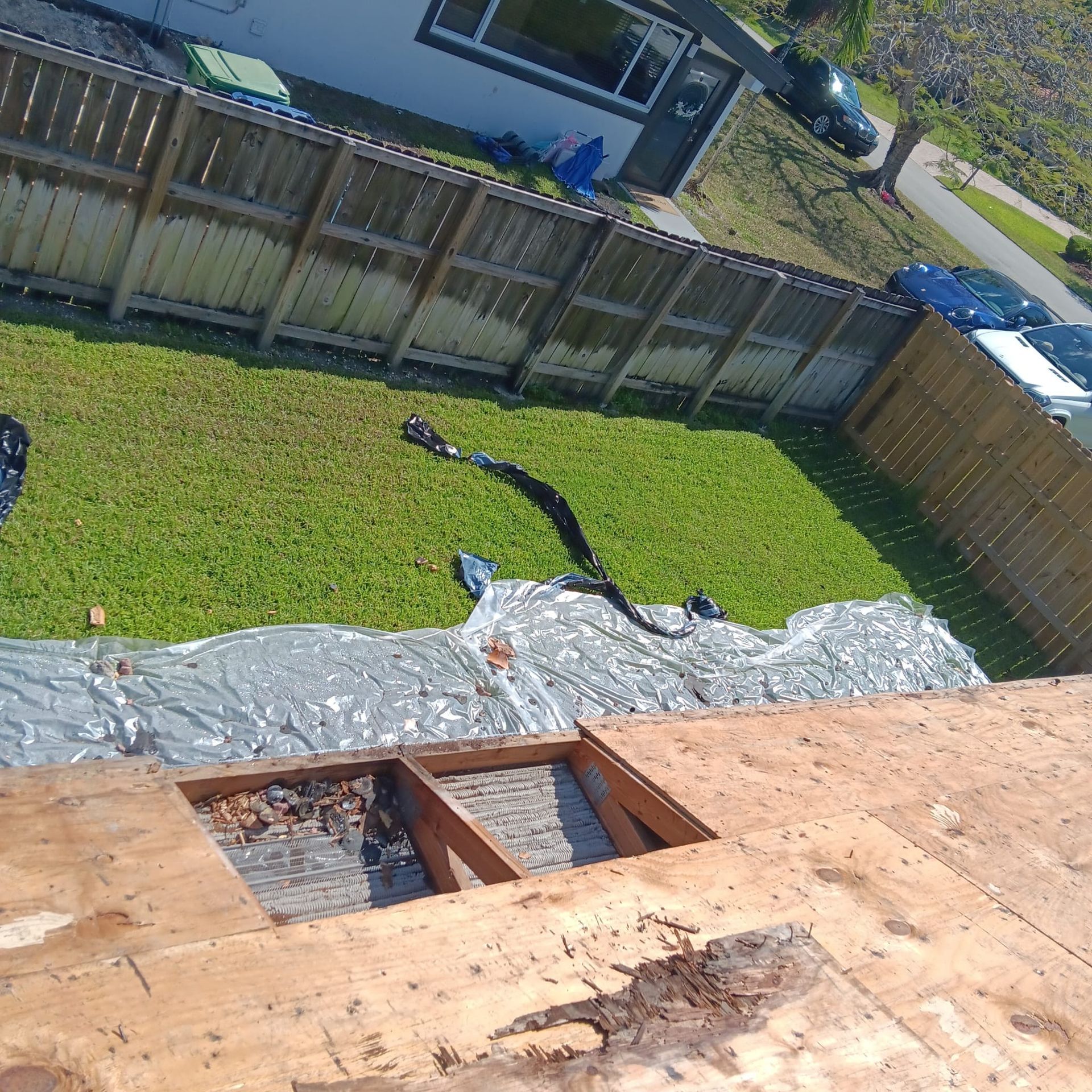 A roof with a hole in it and a fence in the background.