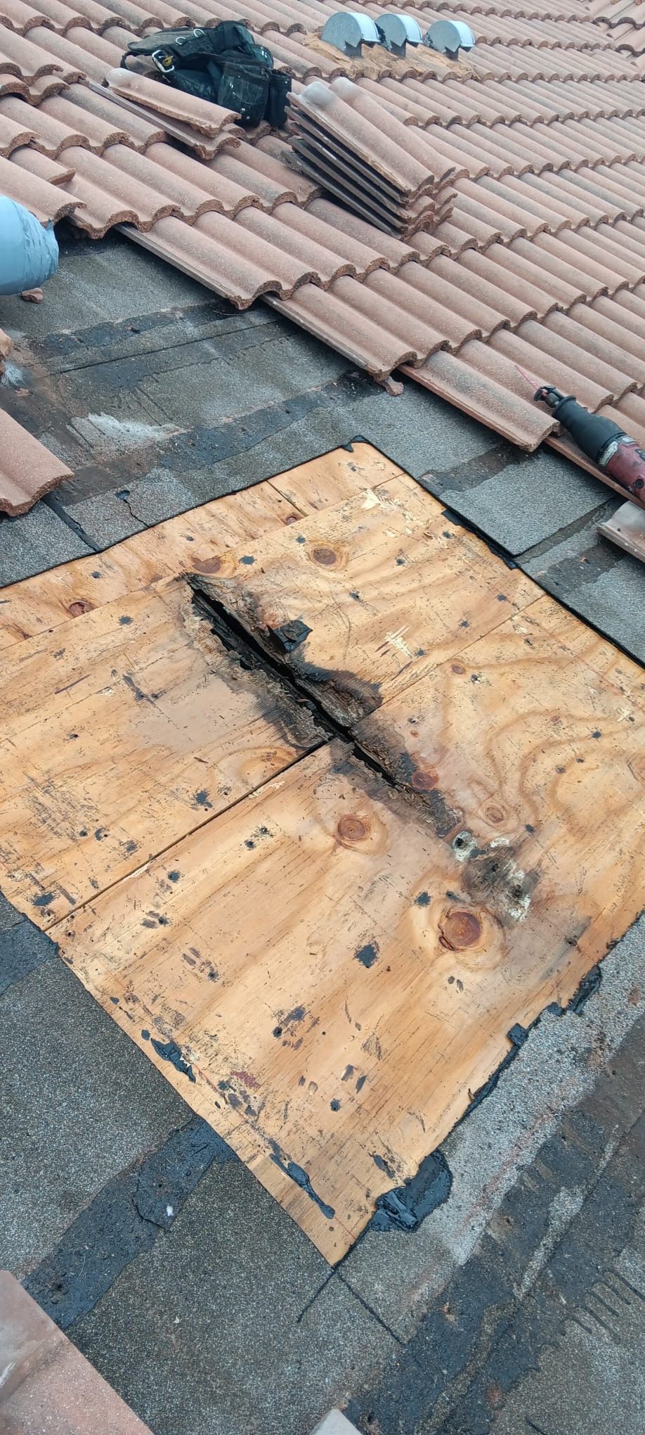 A roof with a hole in it and a piece of wood on top of it.