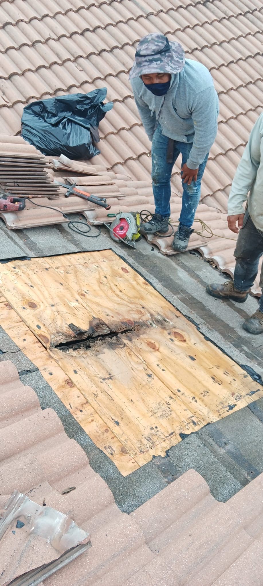 A man is standing on top of a tiled roof.