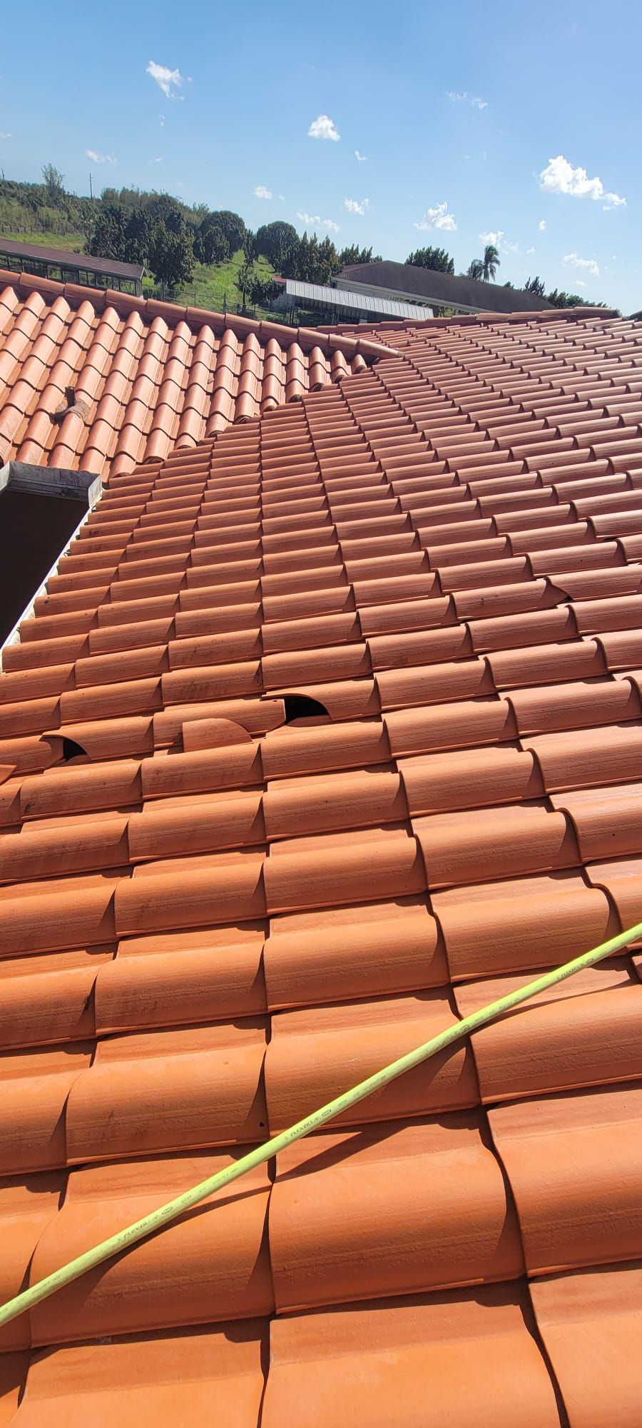 A roof with red tiles and a green hose on it.