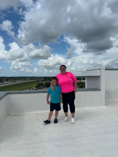 A woman in a pink shirt stands next to a boy in a blue shirt on a rooftop