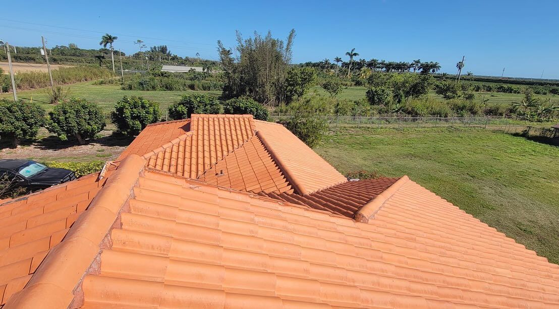 An aerial view of a red tiled roof with a field in the background.