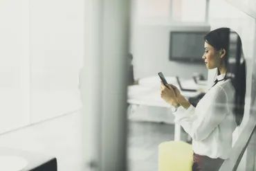 A woman is sitting in a chair looking at her cell phone.