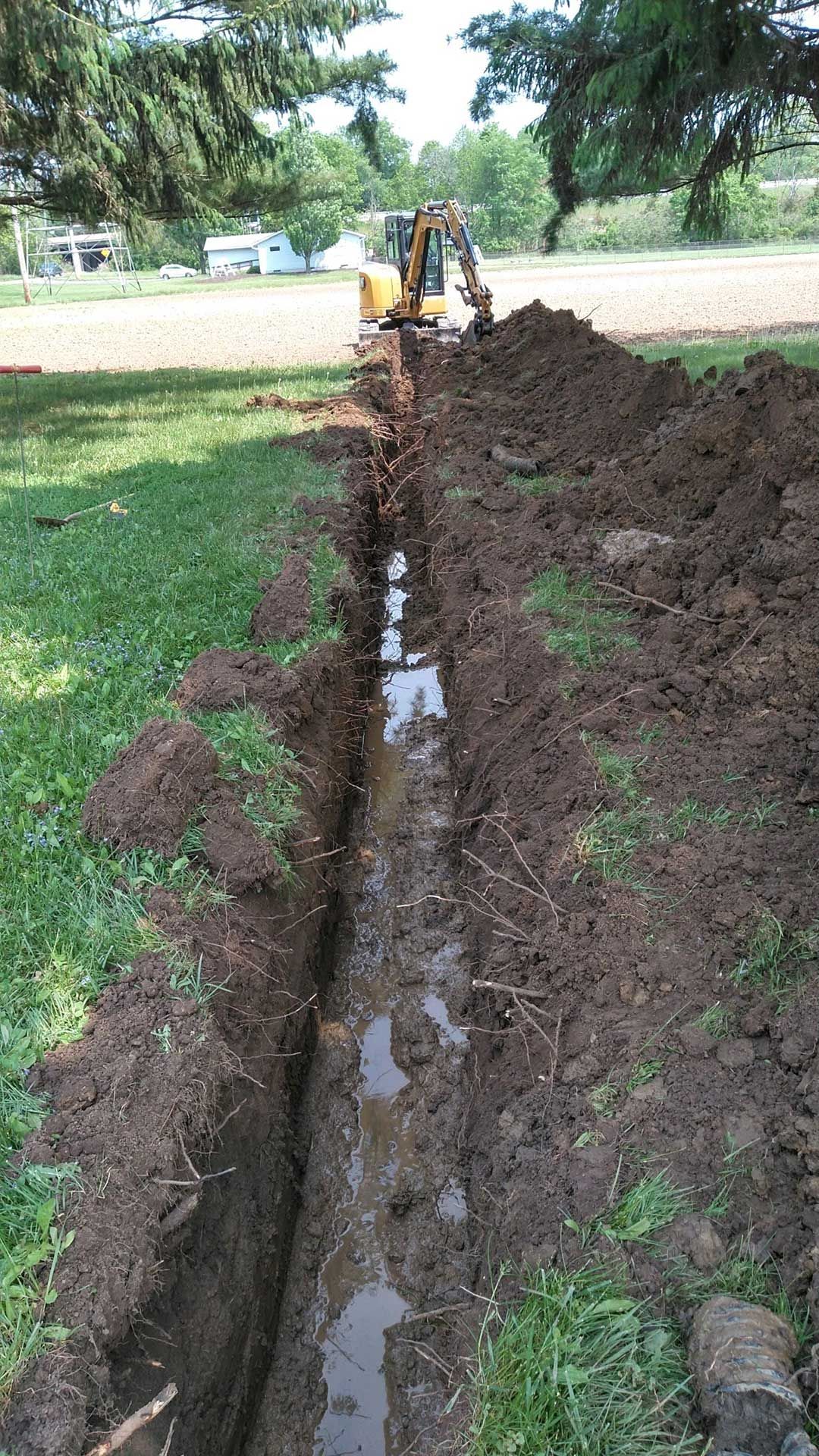 a yellow excavator is digging a trench