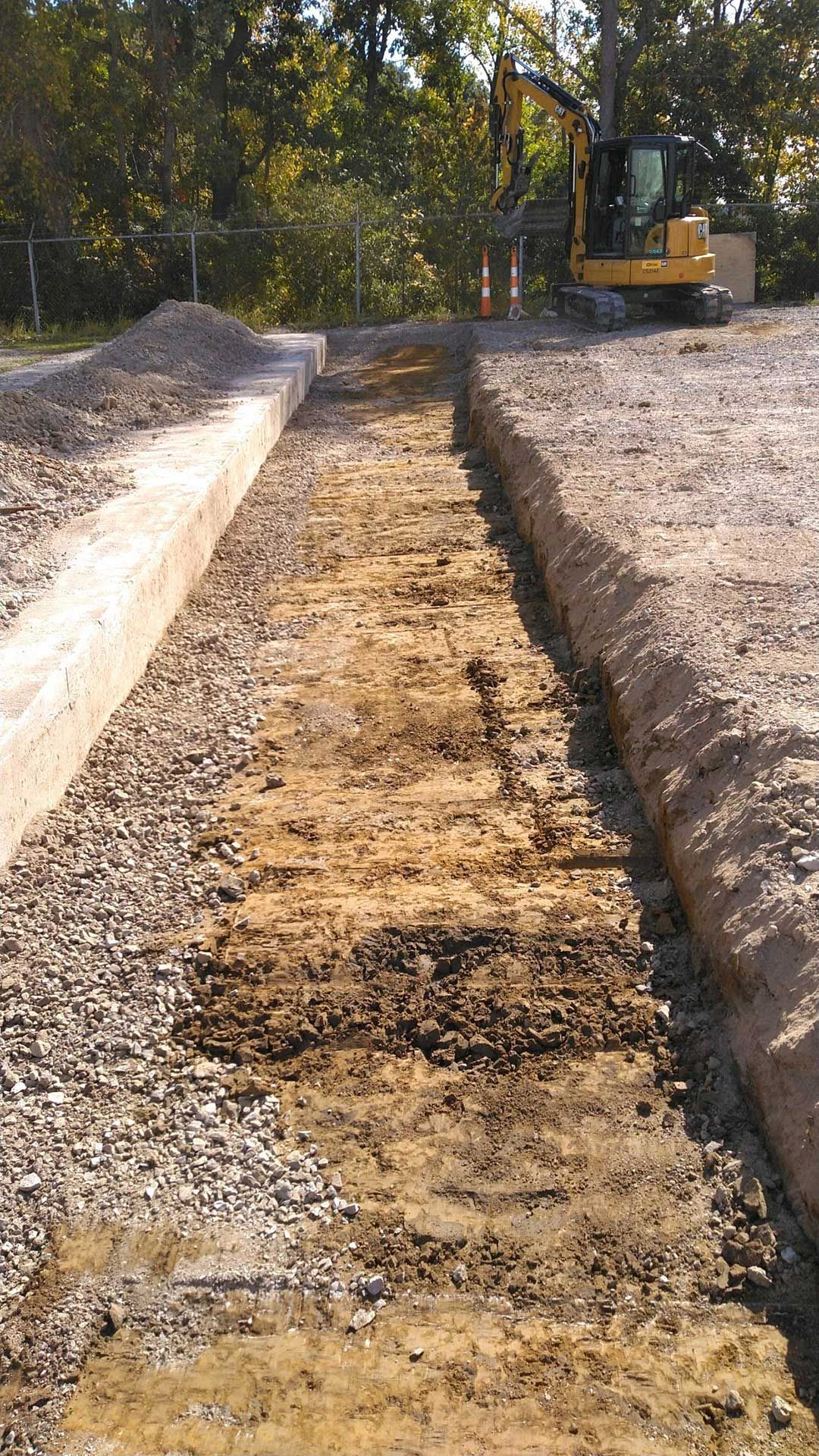 a yellow excavator is digging a trench in the dirt