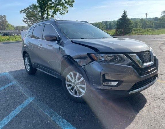 Gray Nissan Rogue SUV with front-end damage parked outdoors.