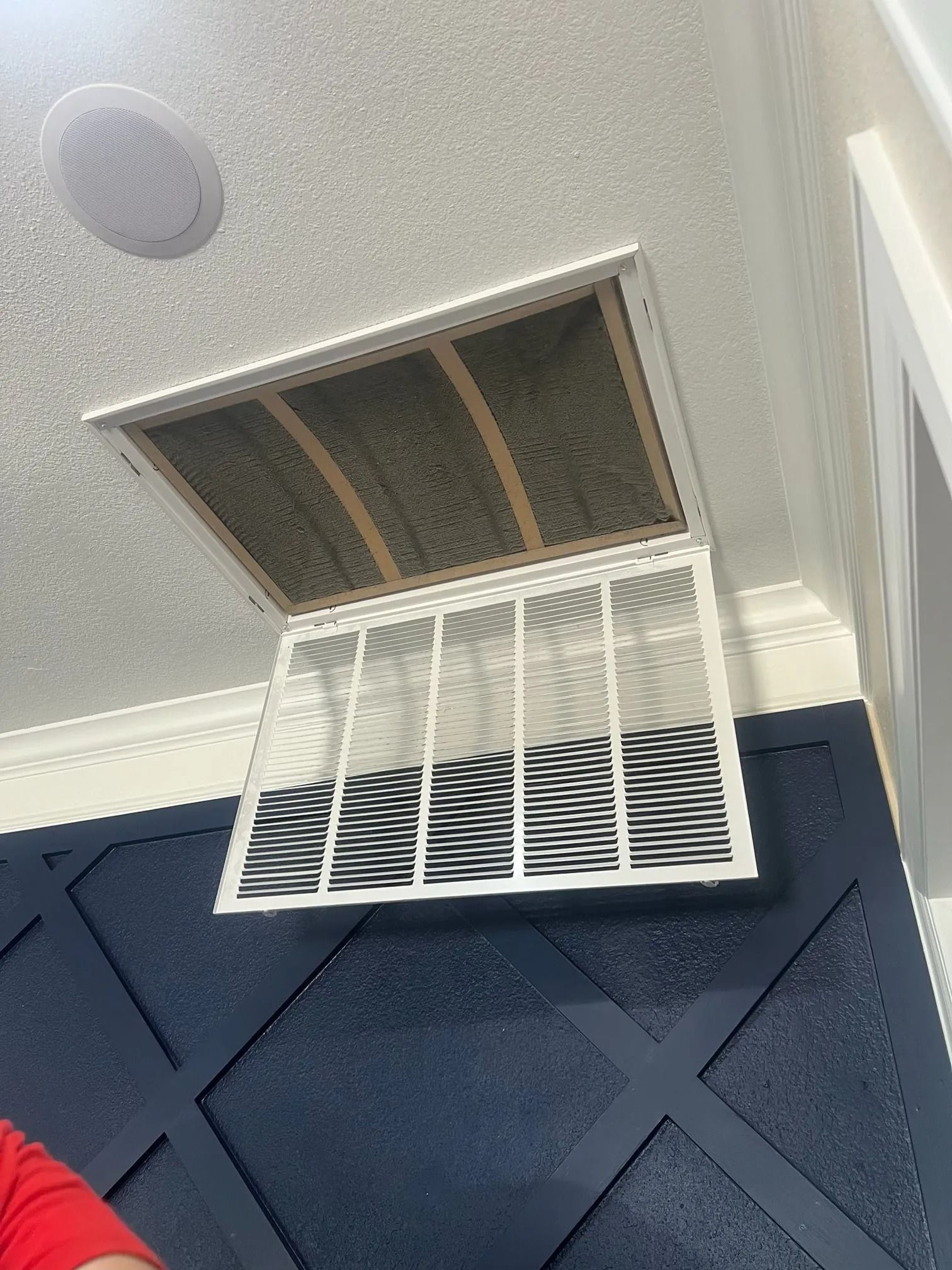 Air vent cover open, revealing a dirty air filter in a white frame, mounted on a blue wall.