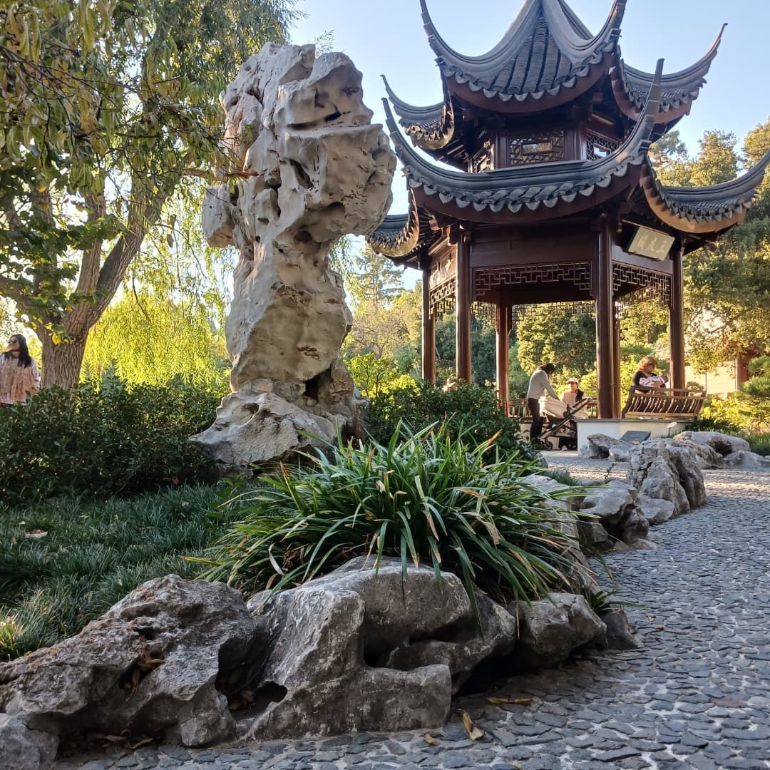 Chinese garden scene with a pagoda, rock formation, and greenery.