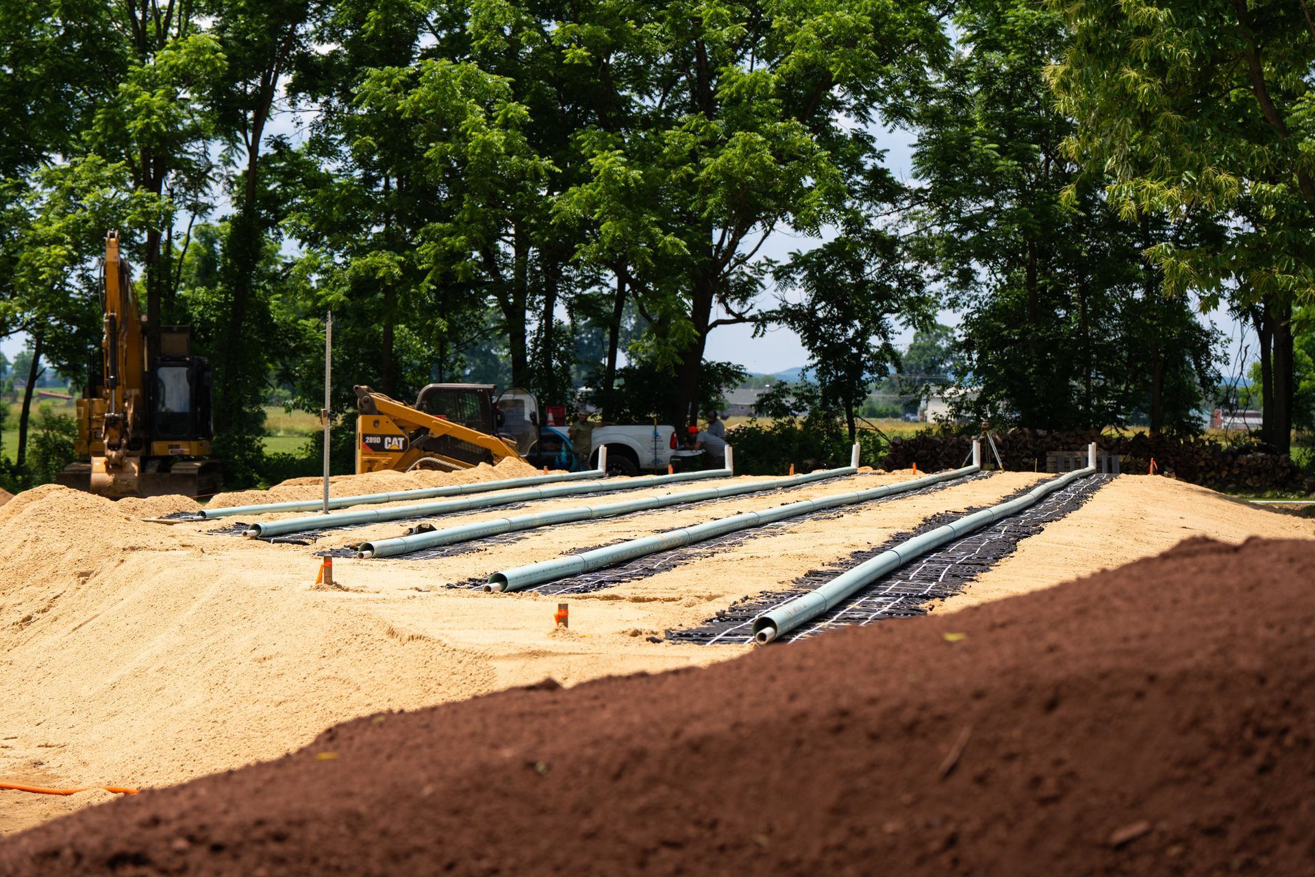 A construction site with a lot of pipes in the dirt