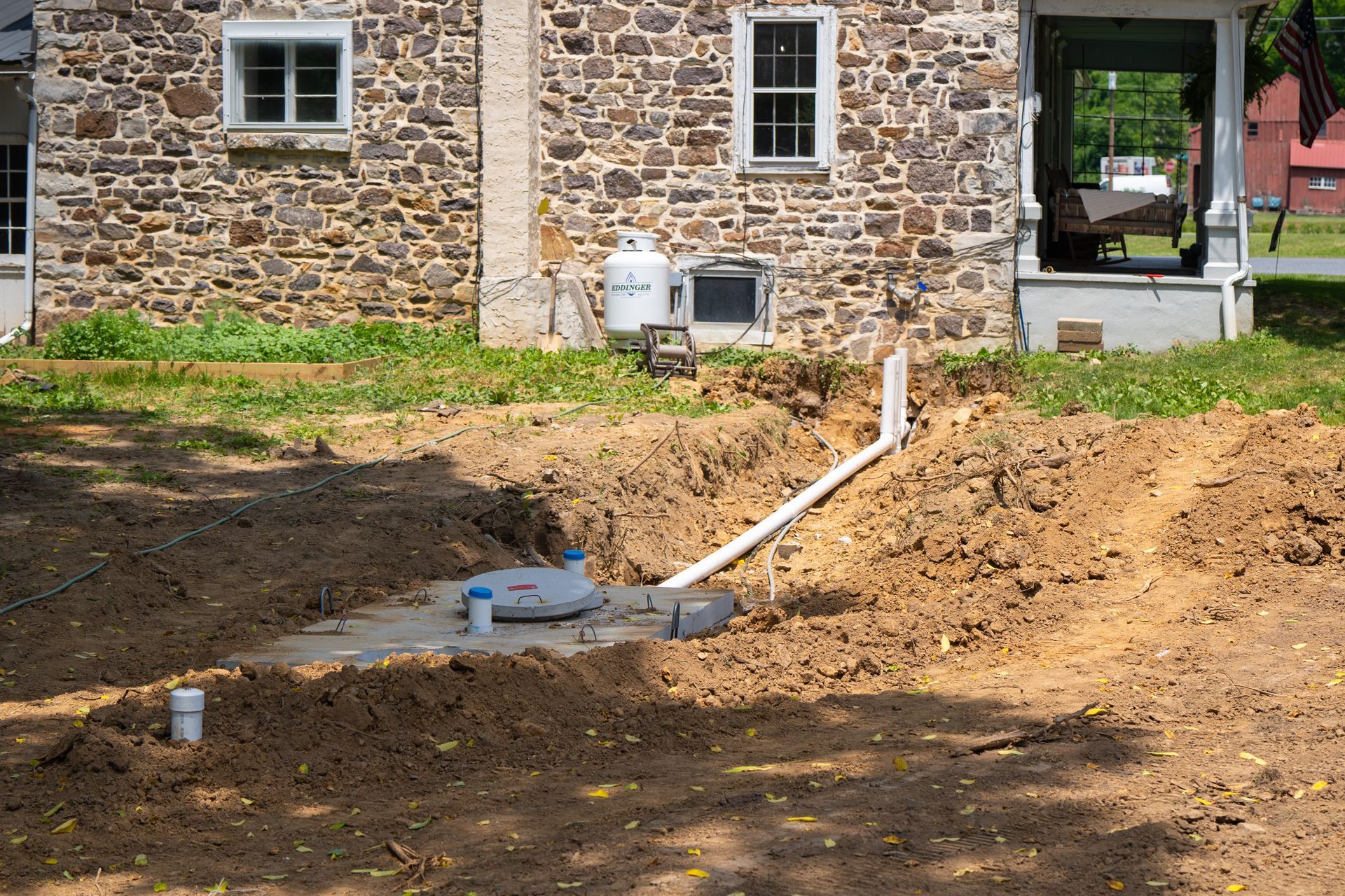 A septic tank is being installed in front of a stone house.