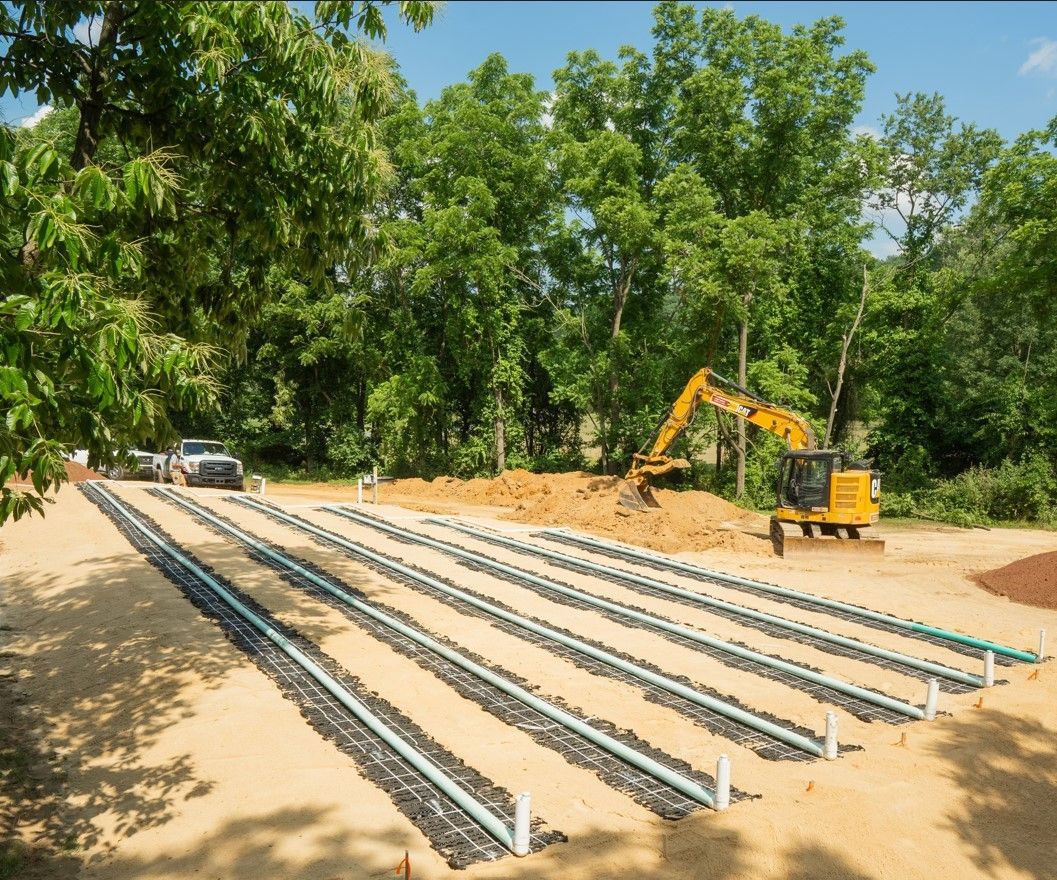 A yellow excavator is working on a septic system.
