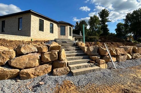 a house with stairs leading up to it is surrounded by rocks and gravel .