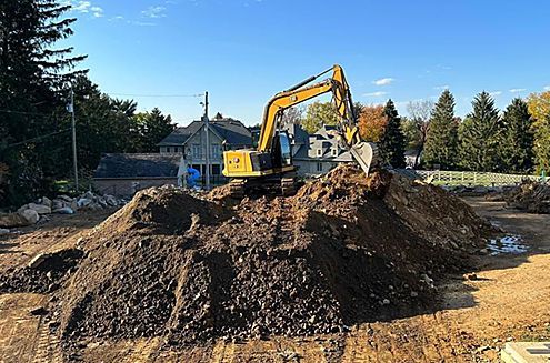 an excavator is working on a pile of dirt in a construction site .