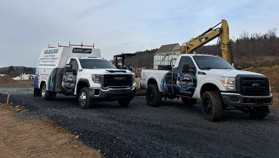 Two trucks are parked next to each other on a gravel road.