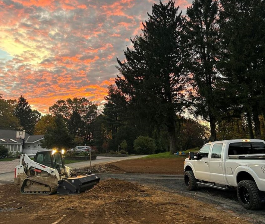 a white truck is parked next to a bulldozer at sunset