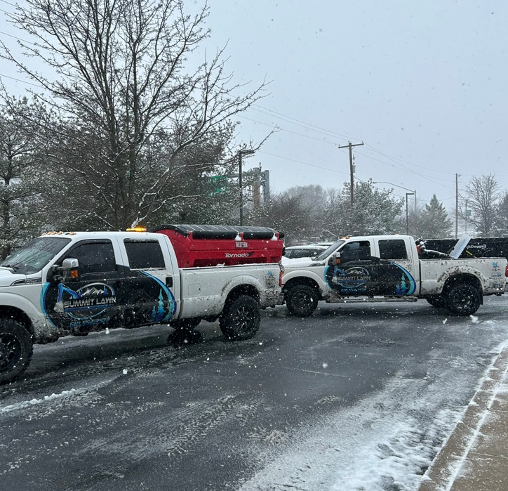 three trucks are parked on the side of the road in the snow .