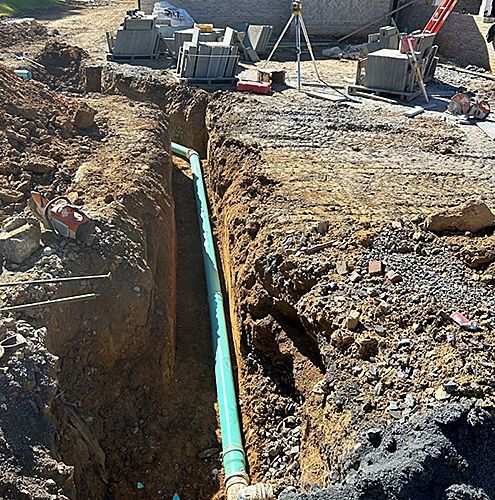 a green pipe is being installed in a hole in the ground .