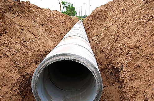 a large concrete pipe is being installed in a trench .