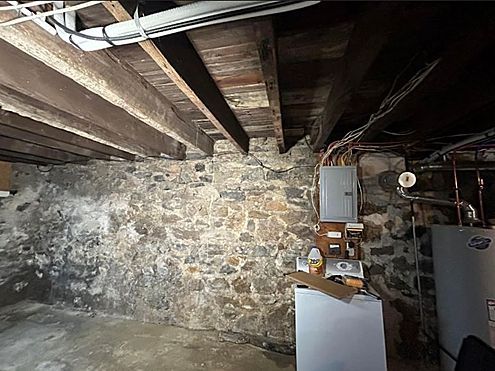 a basement with a stone wall and wooden beams .