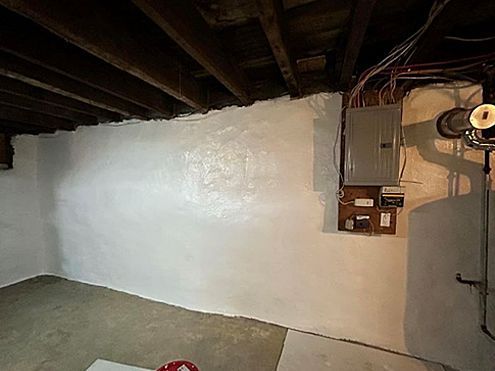 a basement with a white wall and wooden beams .