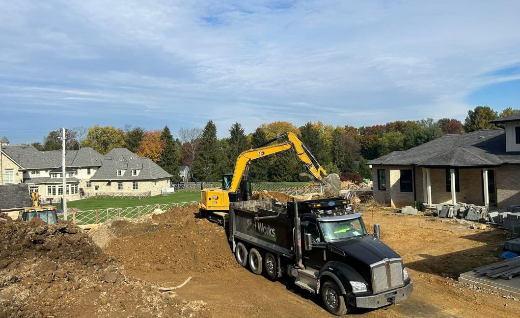 a dump truck is driving through a construction site next to a house
