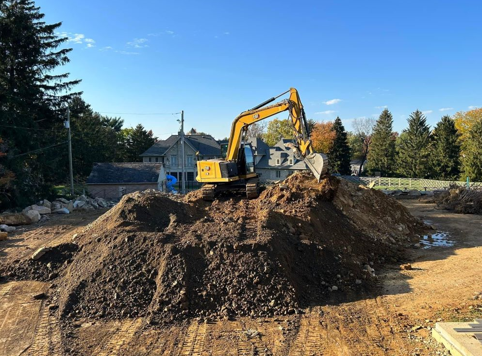 a yellow excavator is sitting on top of a pile of dirt