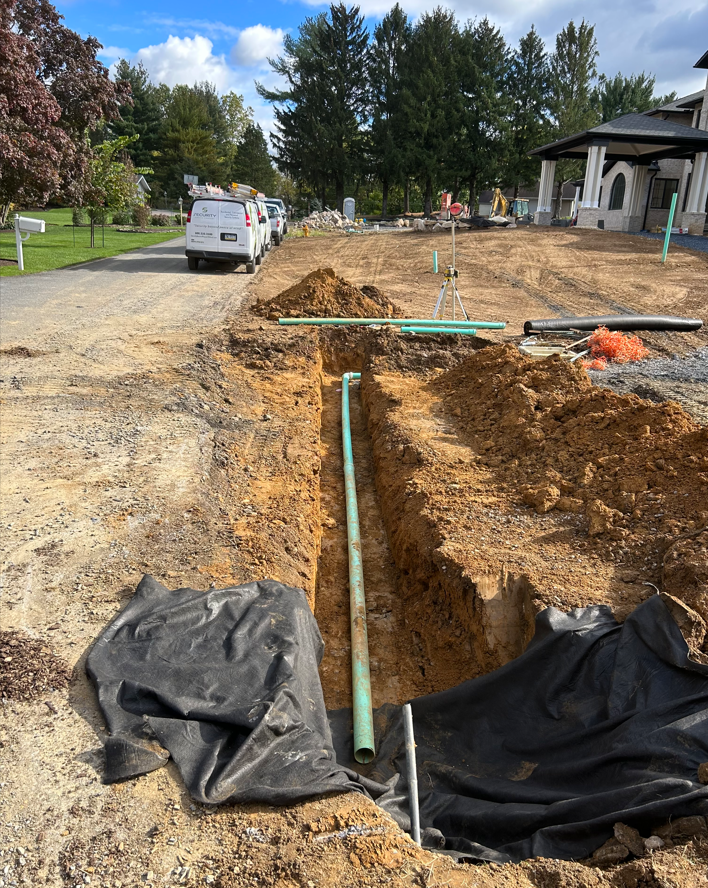 a green pipe is lying in the dirt next to a black tarp