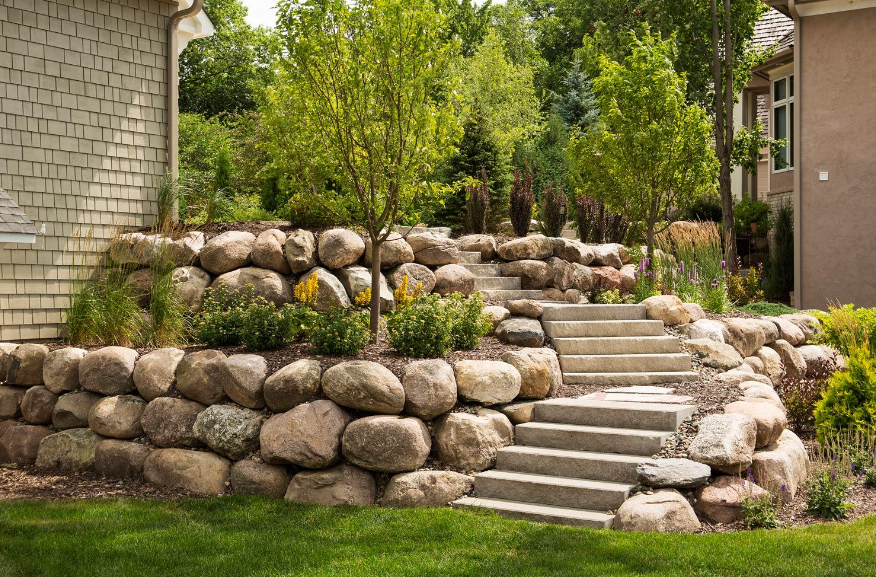 a stone wall with stairs leading up to a house