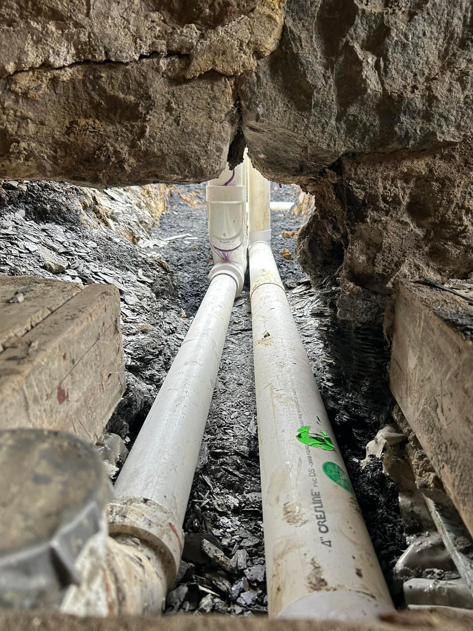 a couple of pipes are sitting in the dirt under a rock .