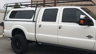 A white truck with a canopy on top of it is parked in front of a building.